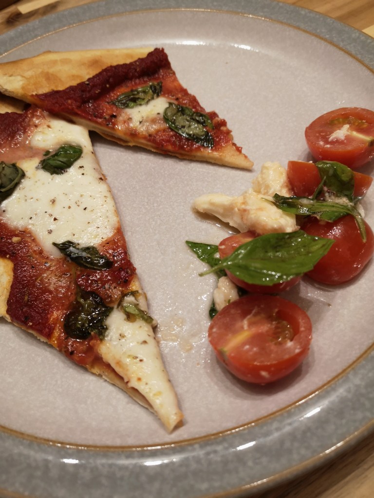 A margarita pizza slice and a caprese side salad