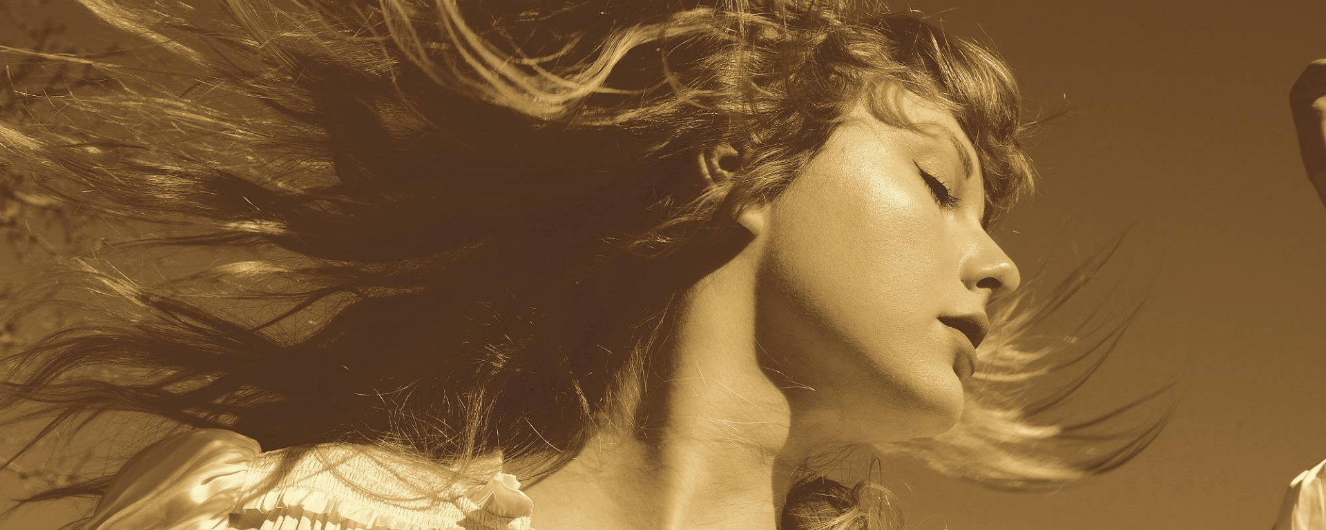 Taylor Swift looks to the right, her hair splaying out from the movement, her eyes are closed and she is wearing a frilly white blouse. The photo has a sepia style filter on it