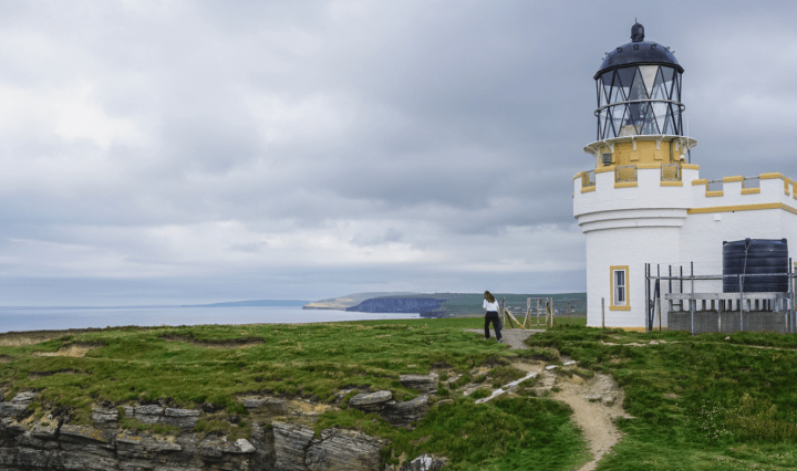 A white and yellow lighthouse on a grassy island