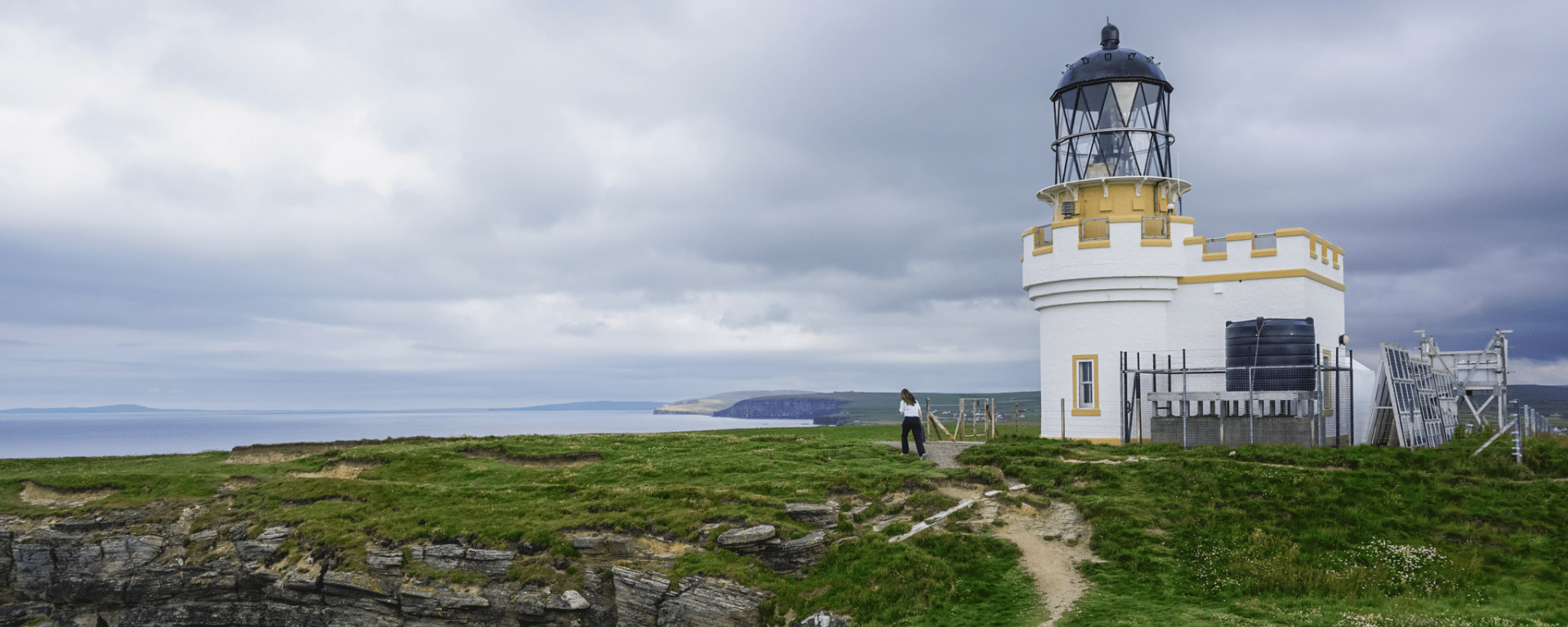 A white and yellow lighthouse on a grassy island