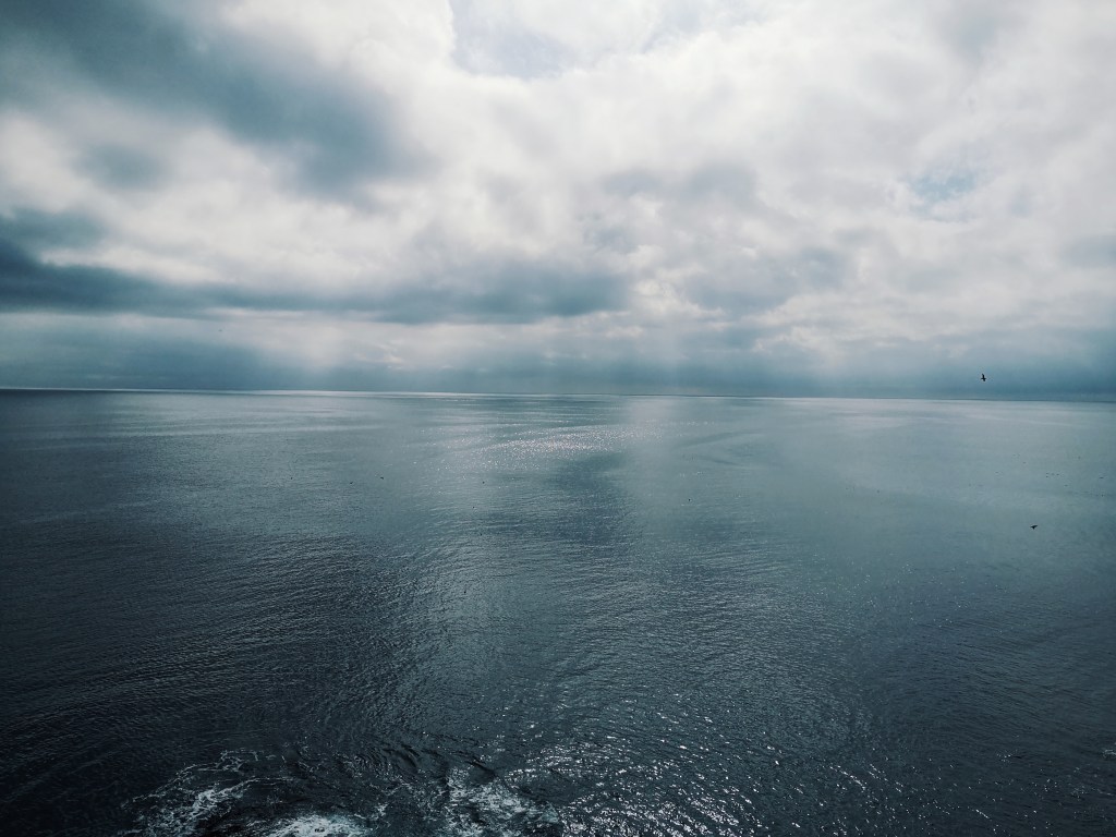 Light pours through the cloud onto the shiny sea