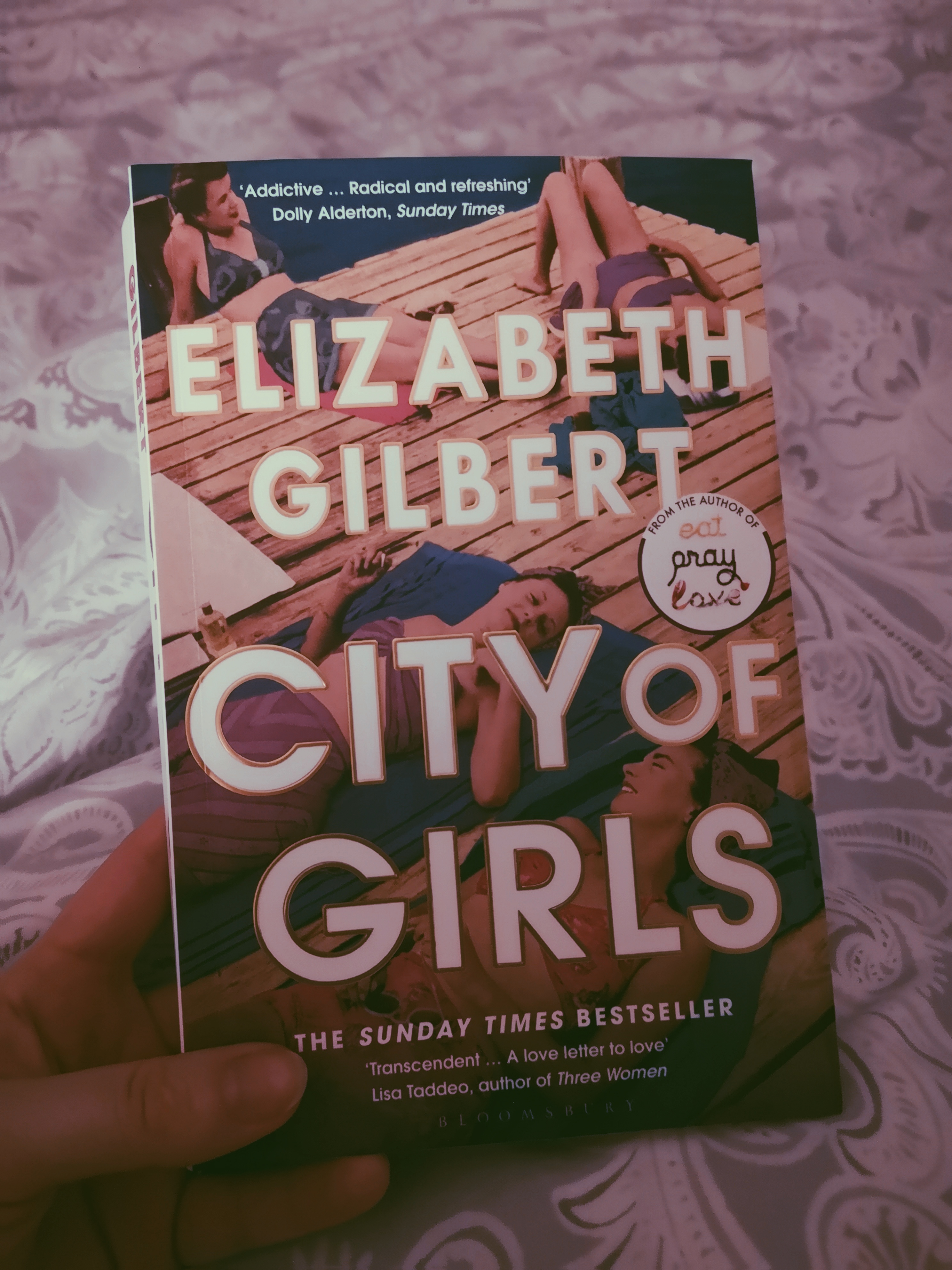 A hand holds City of Girls by Elizabeth Gilbert