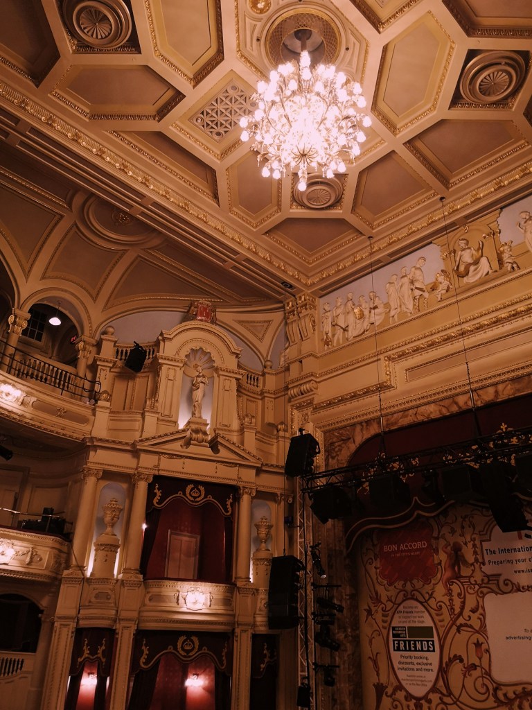 Looking up at the ceiling of an ornate theatre and chandelier