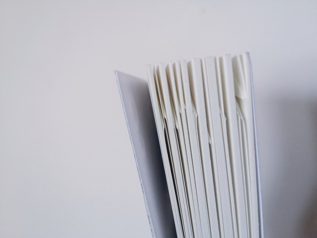 A close up image of a closed book with many dog ear folded down in the pages throughout
