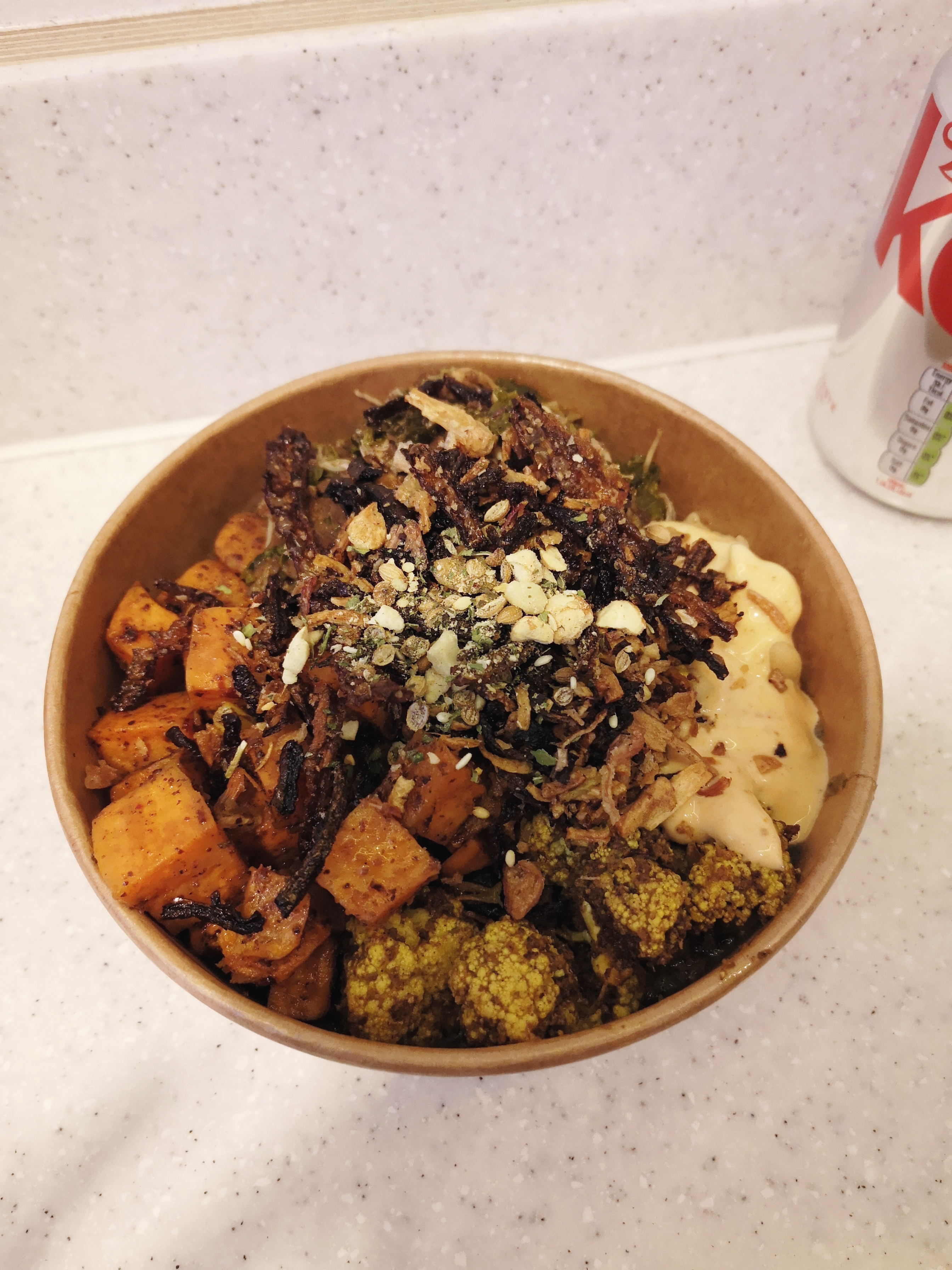 A bowl of vegetables and grains with crispy onions and mayo on top