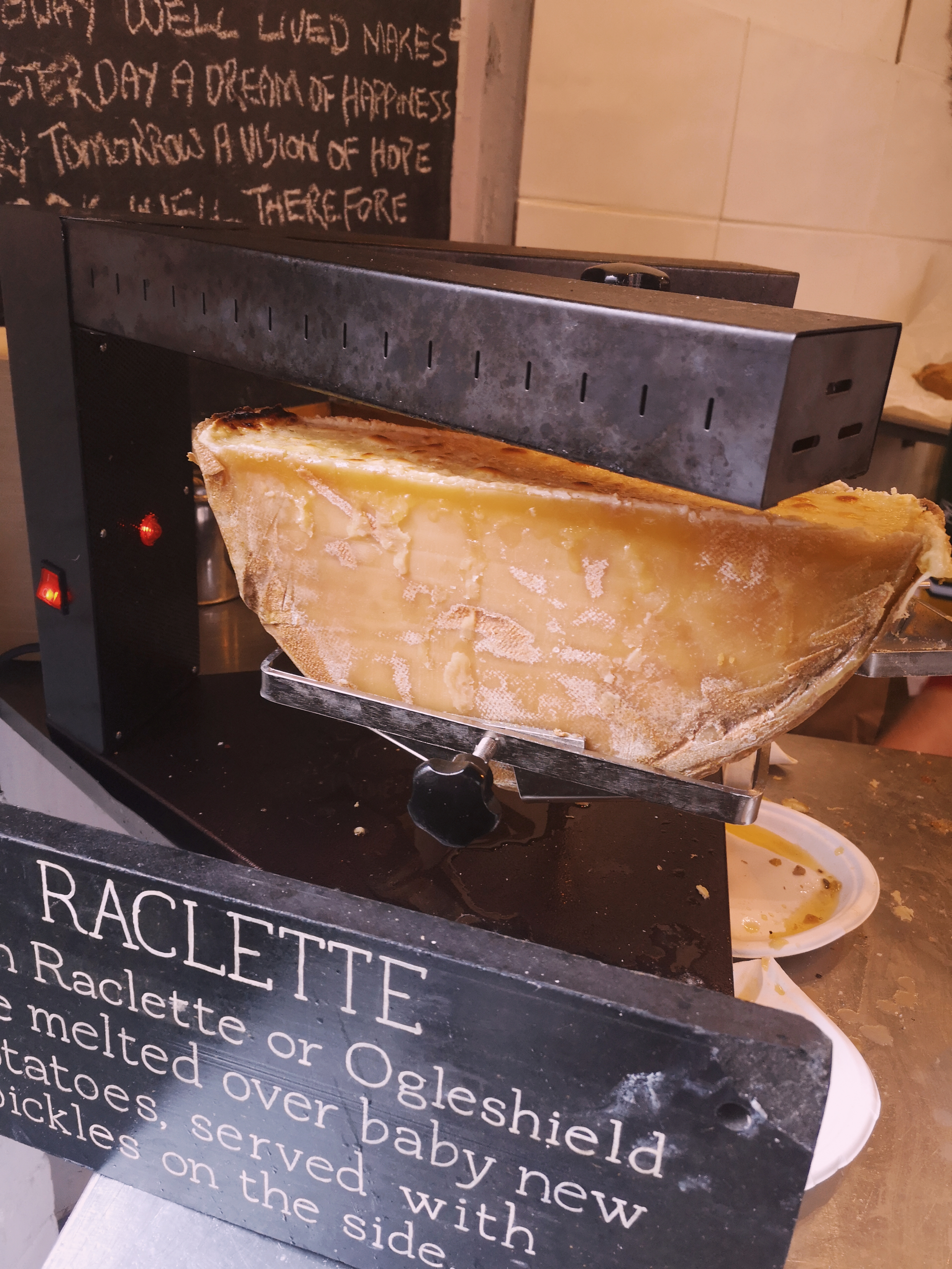 A semi-circle block of cheese sitting under a heat lamp