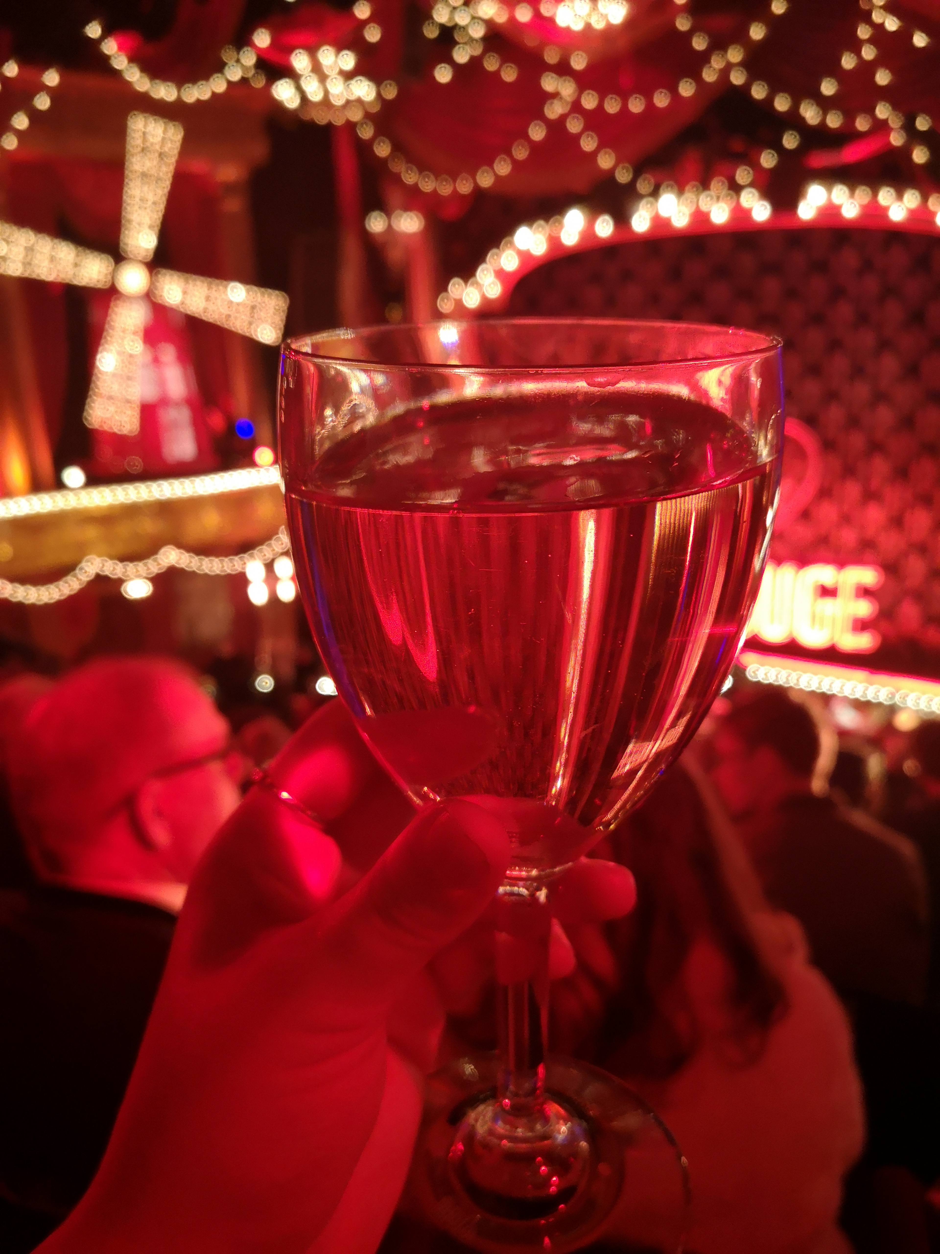 A glass of wine held infront of red lights making it glow
