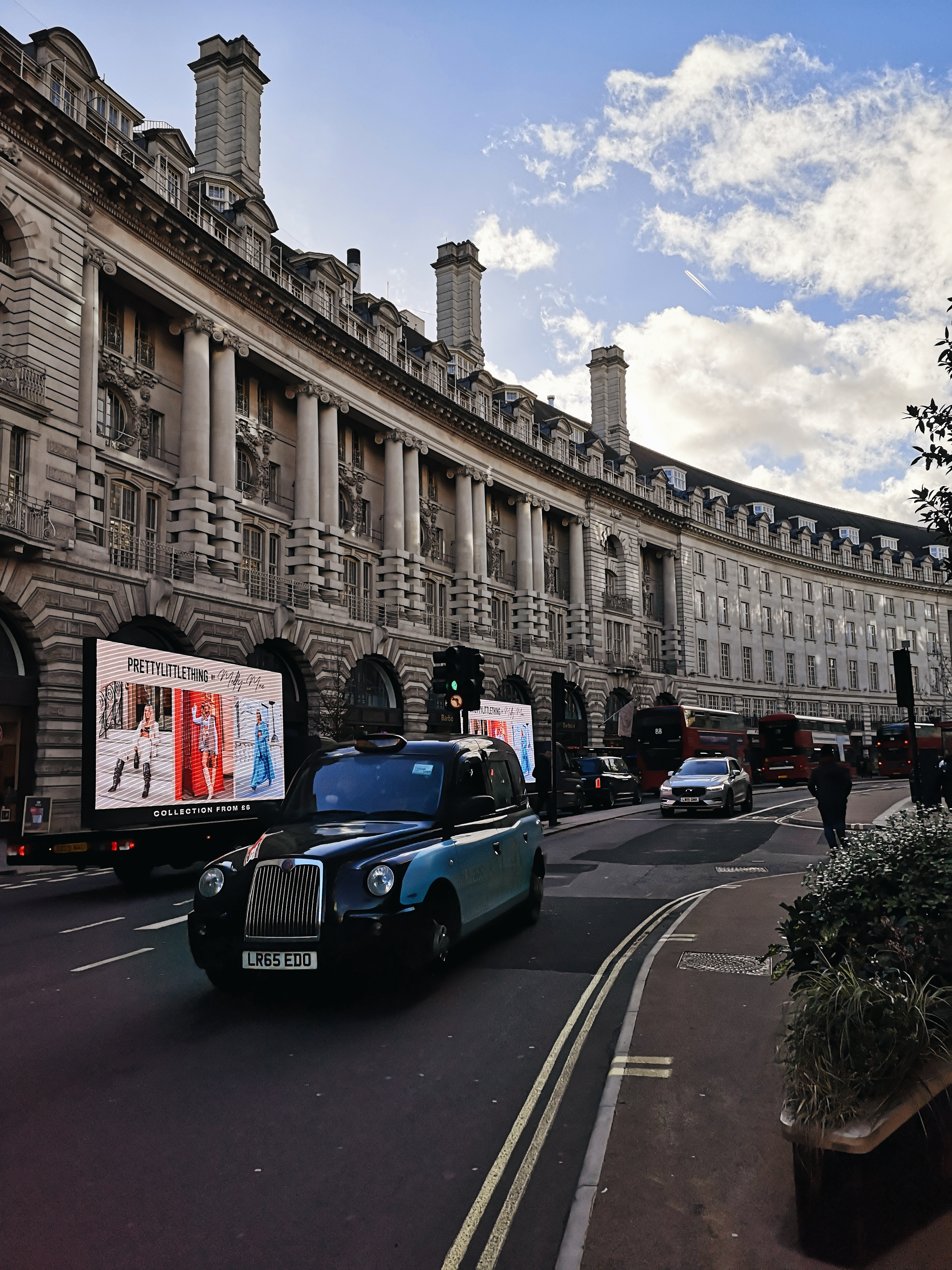 A London street with big white pillared buildings and a black cab on the road