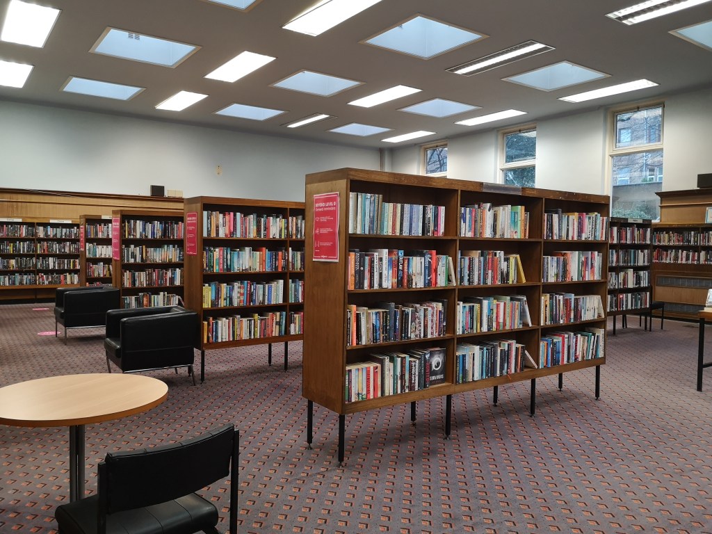 Rows of books are stacked on wooden shelves