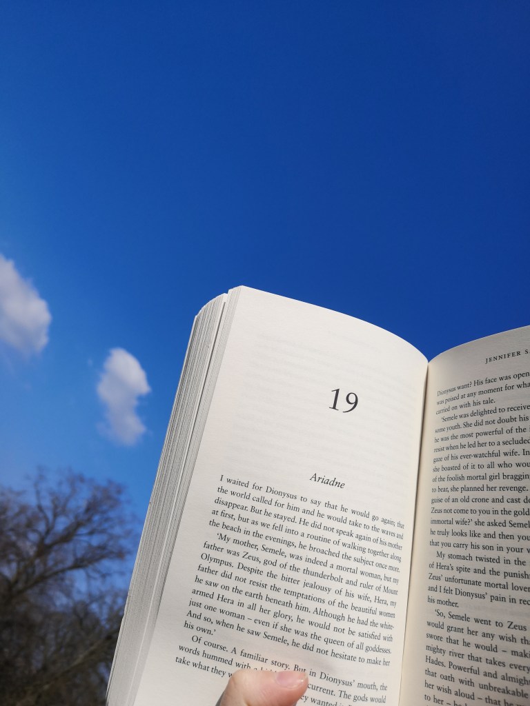 An open book held up against a blue sky as I read in the sunshine