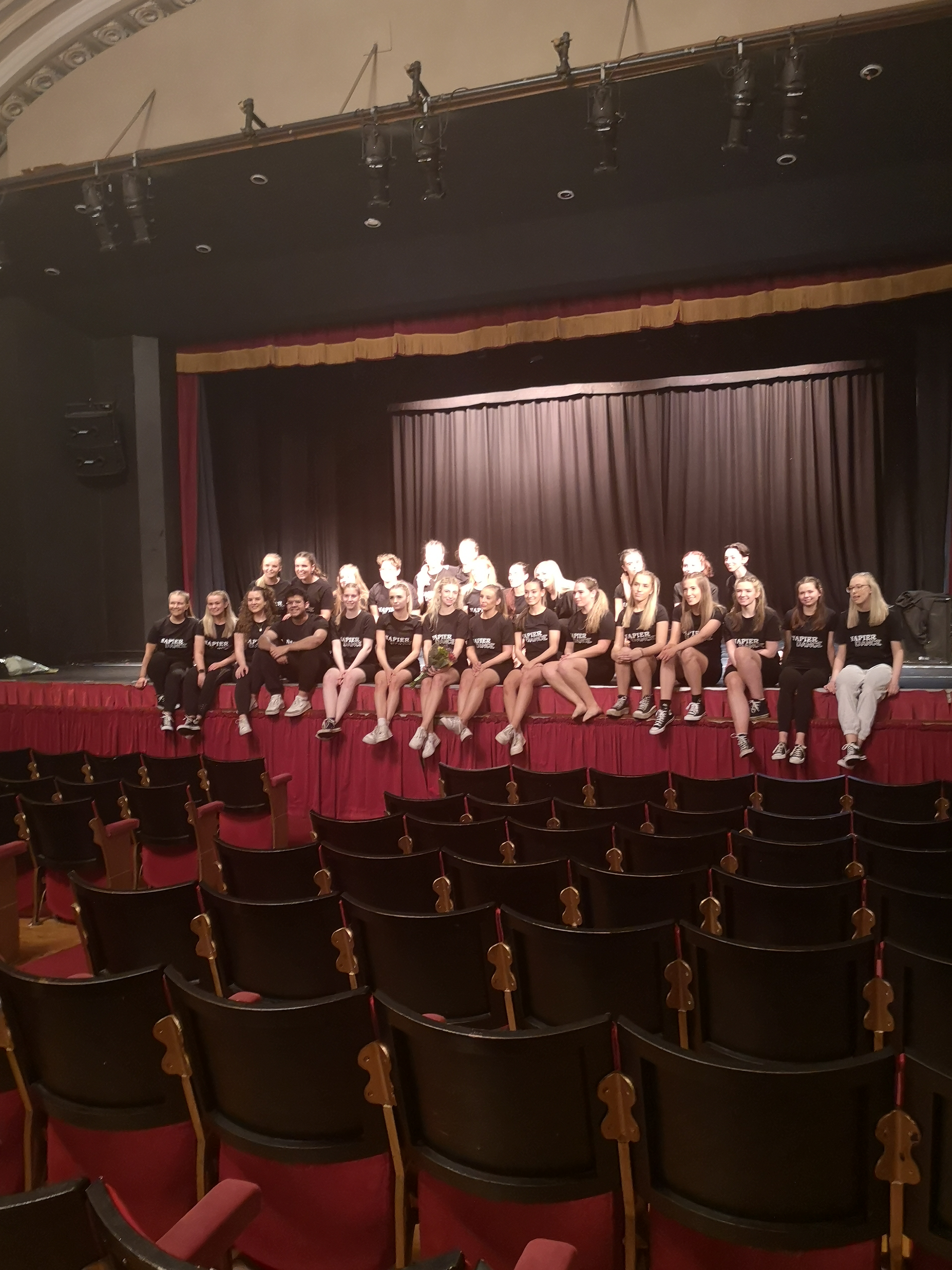 The members of Napier Dance sit on a stage for a group photo