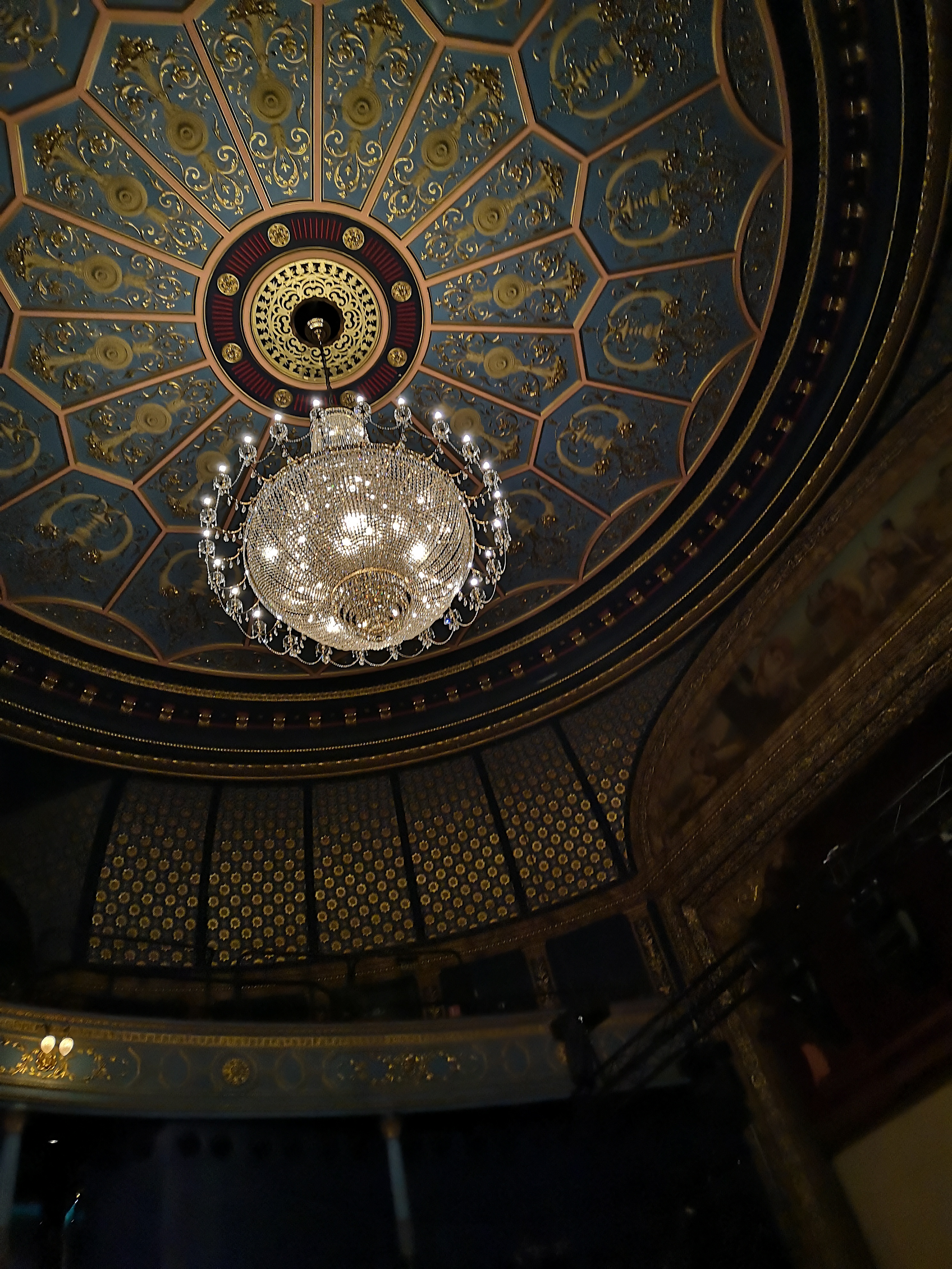 The ceiling of the Lyceum Theatre, it is blue and gold, circular and shining in details. In its centre is a stunning chandelier 