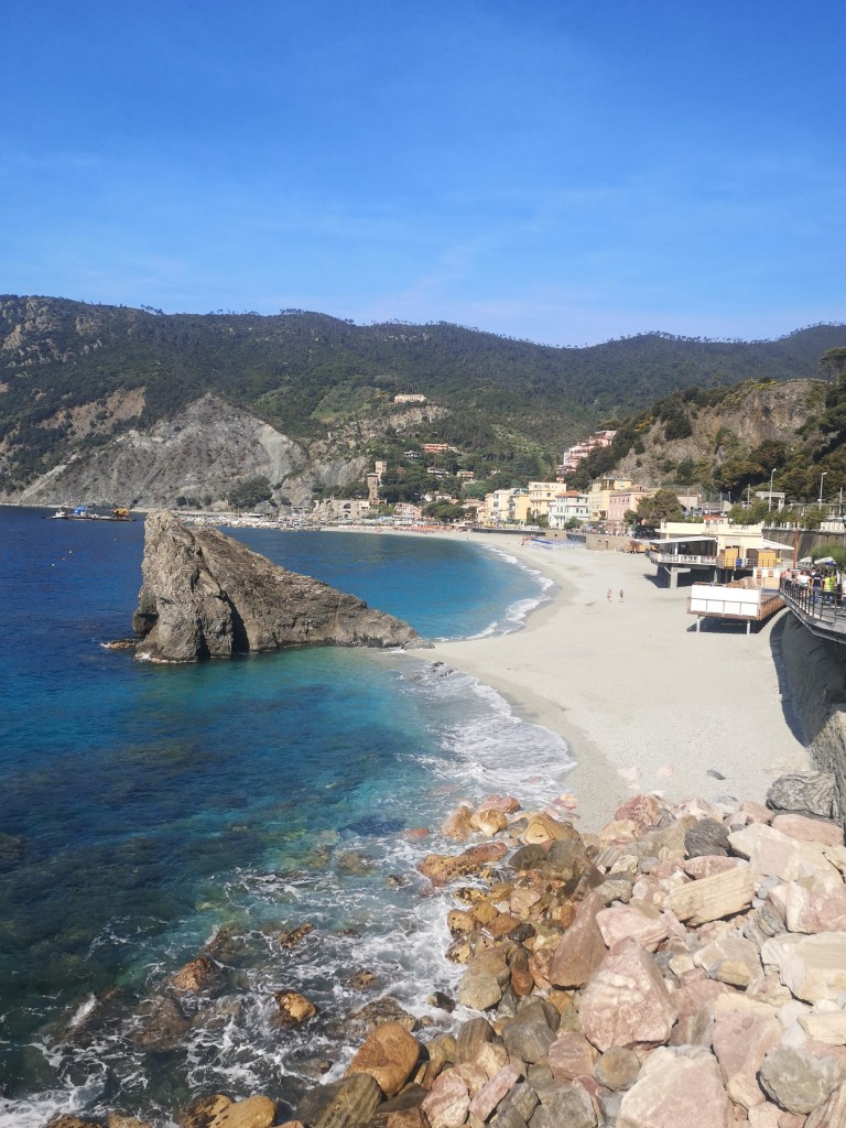 A picture of the Monterosso beach, with a big triangular rock in the middle