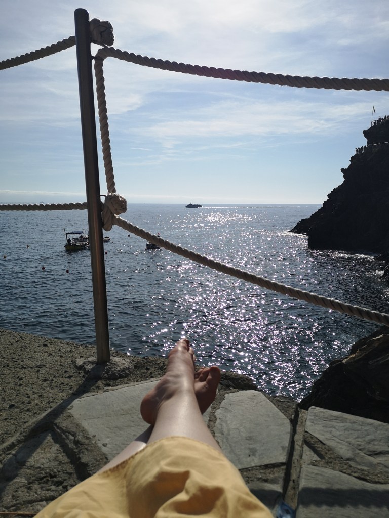 My legs as I sit looking out over the sea, sunlight glittering off the water