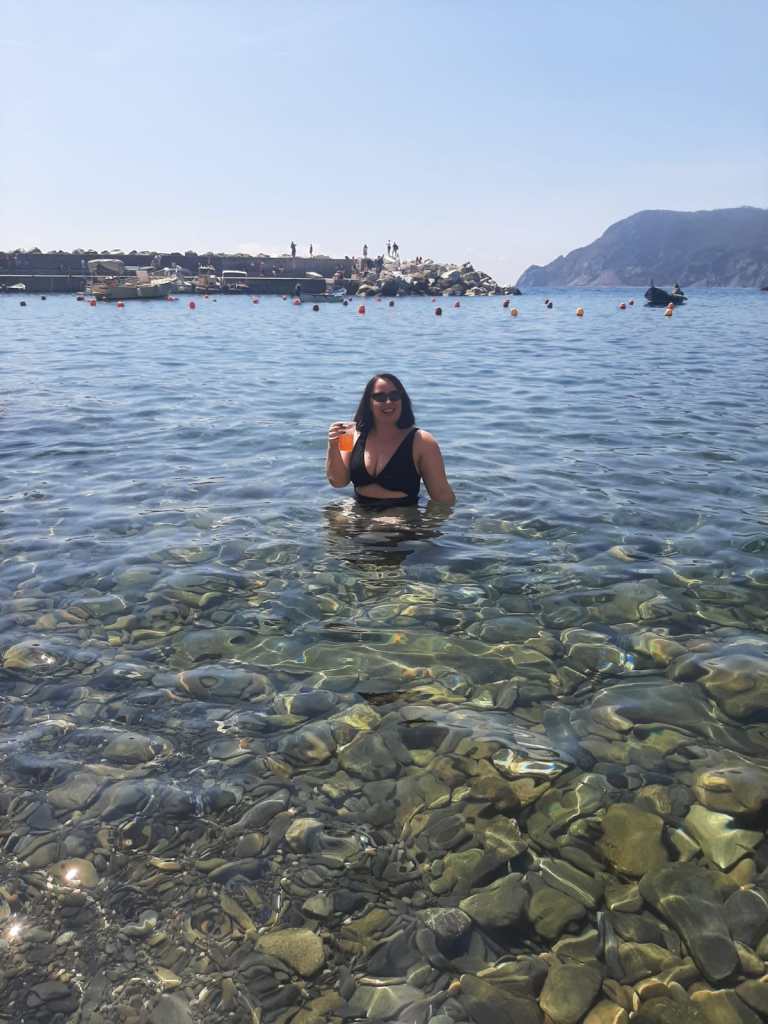 Lil Katie sits in the sea again, but this time with an Aperol spritz in hand