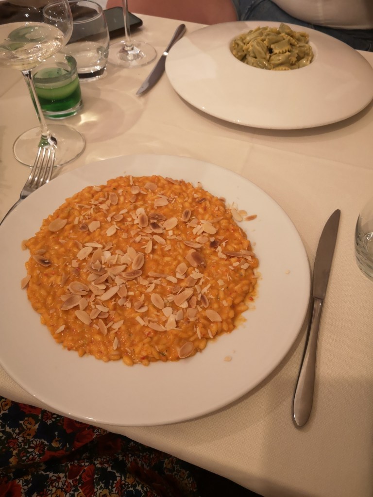 A plate of orange risotto topped with flaked almonds
