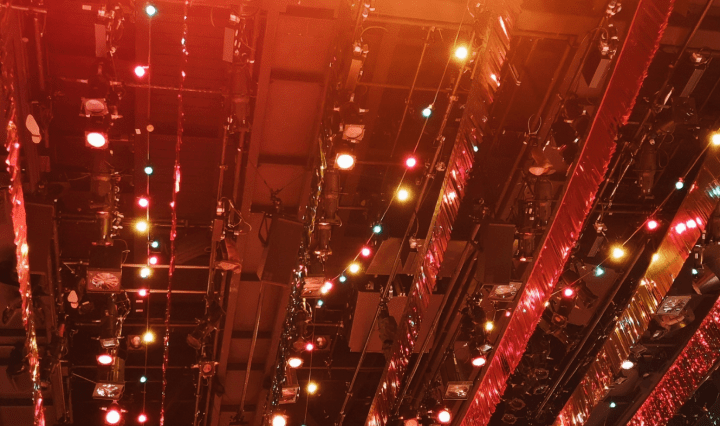 Strings of shiny streamers and lights hang from the ceiling putting an orange glow over the image