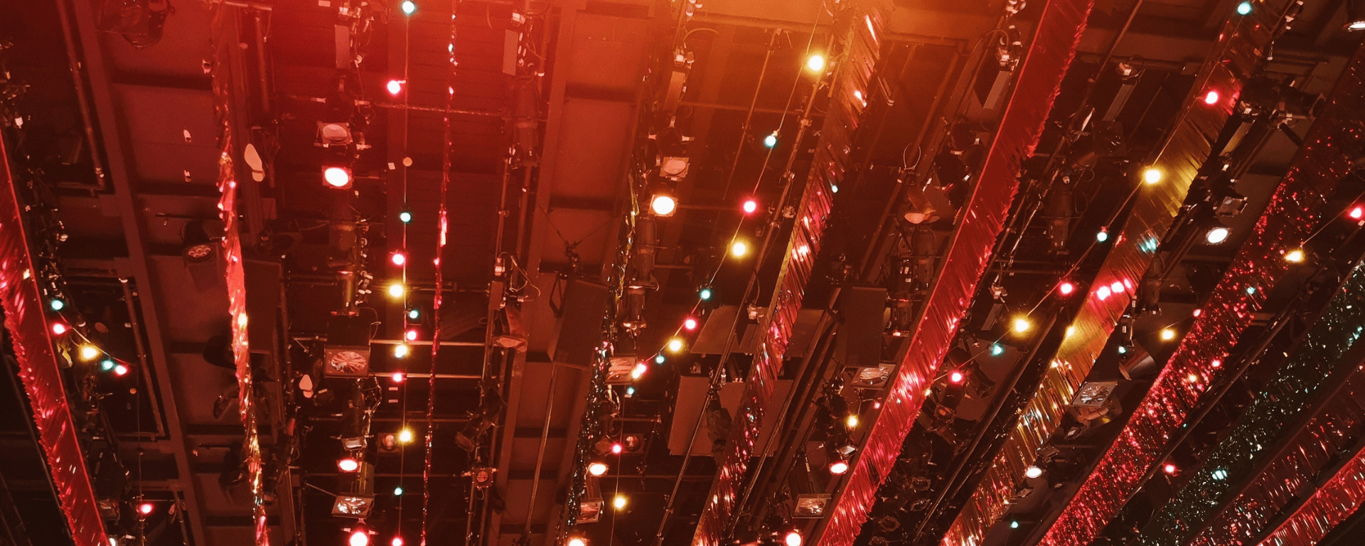 Strings of shiny streamers and lights hang from the ceiling putting an orange glow over the image