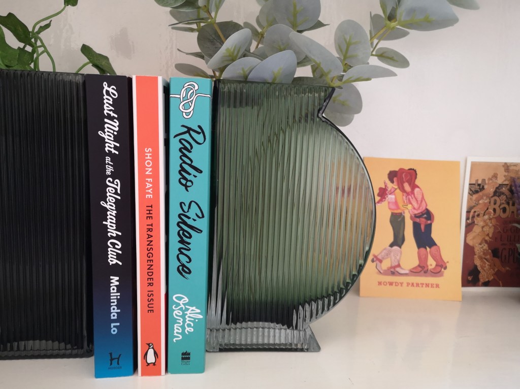 My tbr section, the three books mentioned above are sandwhiched between my vase bookends which have plants in them
Also in the background is an illustration by my friend of two cowboys hiding behind one of their hats, presumably kissing and it says 'howdy partner'