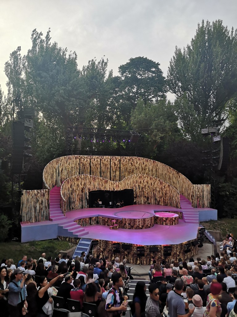 The stage of Legally Blonde is heart shaped with two staircases going up each side. The floor is pink and the curtains are fringed and look like blonde hair 