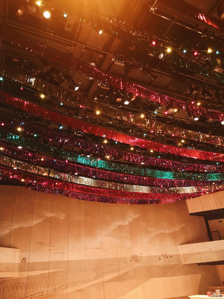 An image of a farm is drawn on the wooden wall of the theatre and coloured streamers and lights hang from the ceiling