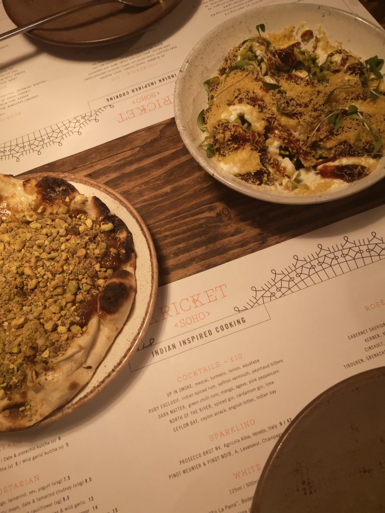 Two dishes on a table - a pistachio covered naan bread and a tasty dip