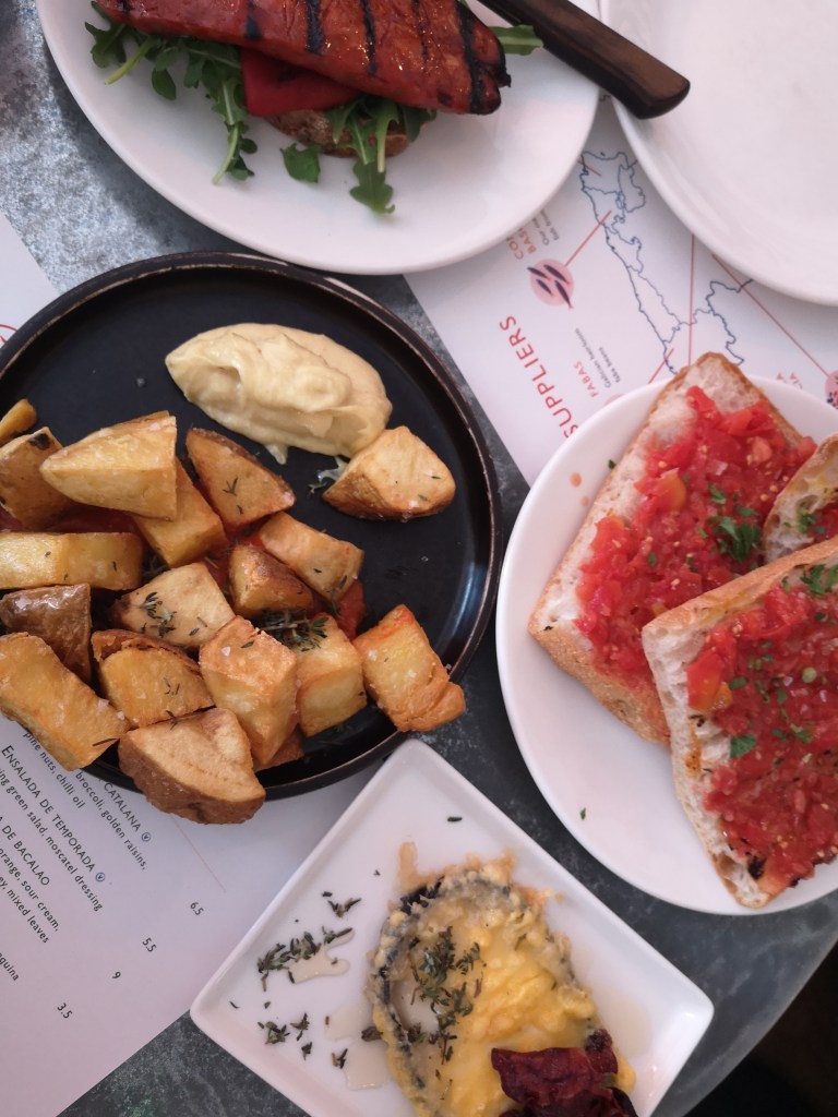 Tapas on the table including a tasty looking chorizo, some patatas bravas and bruschetta