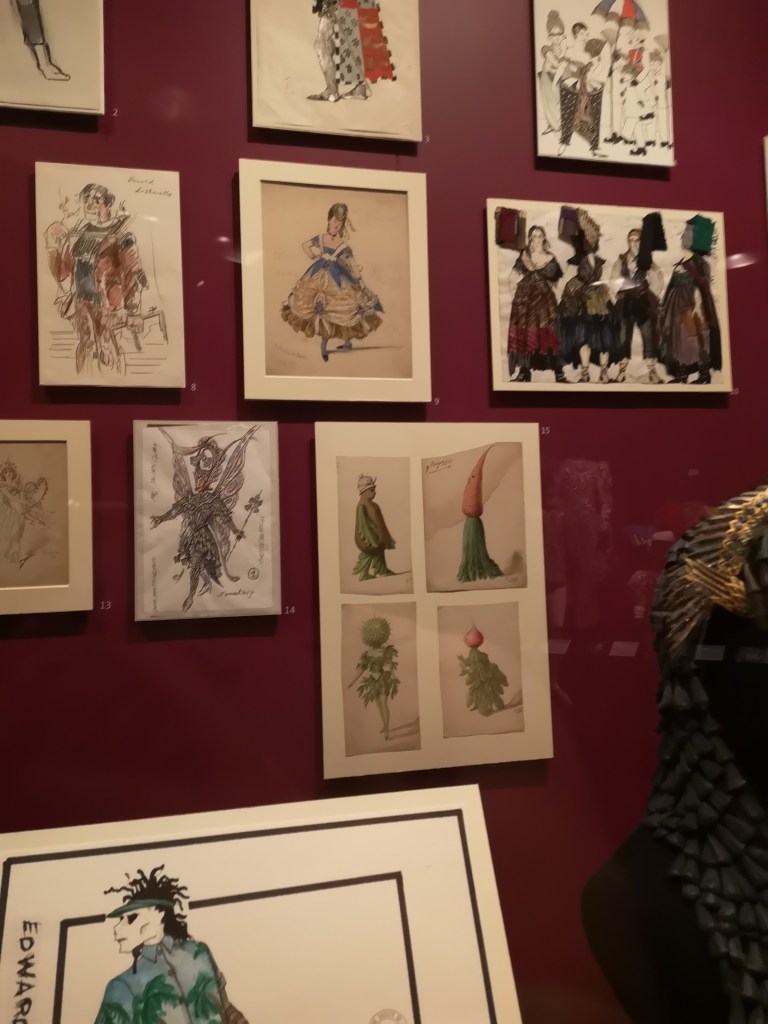 various costume sketches hung on a wall
