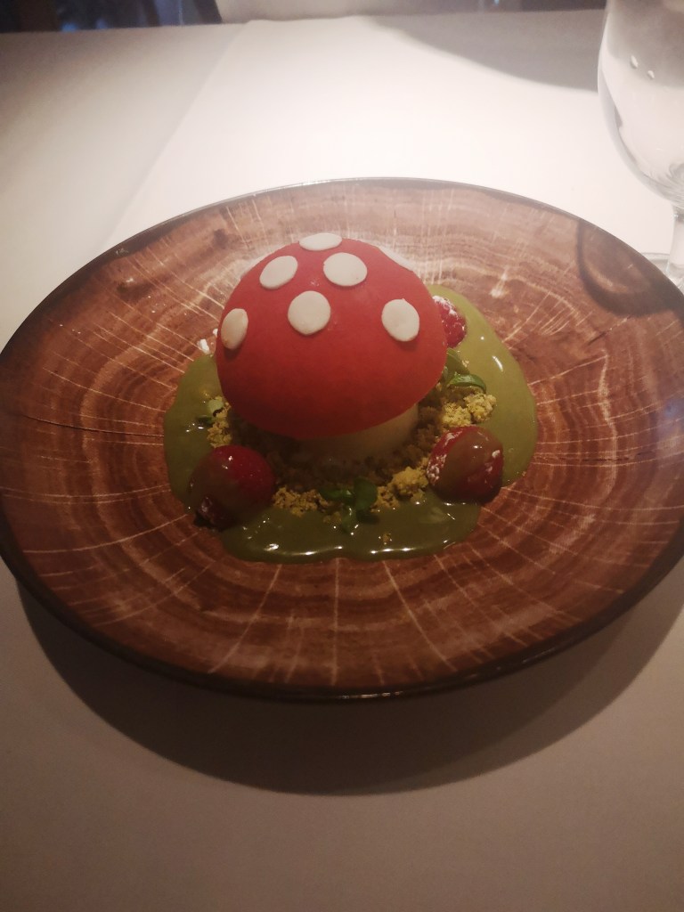 A dessert that looks like a little red and white mushroom but is actually filled with white chocolate and raspberry cream
