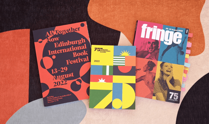 Three brochures sit on top of a colourful rug, they are advertising the Edinburgh Book, International and Fringe festivals