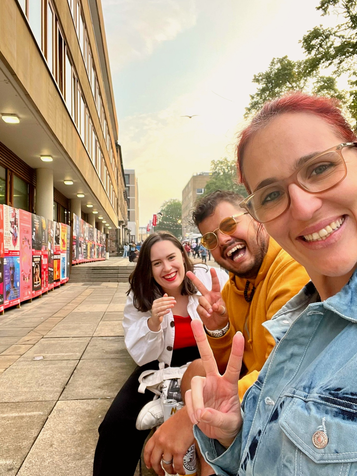 Three smiley people throwing a peace sign and laughing