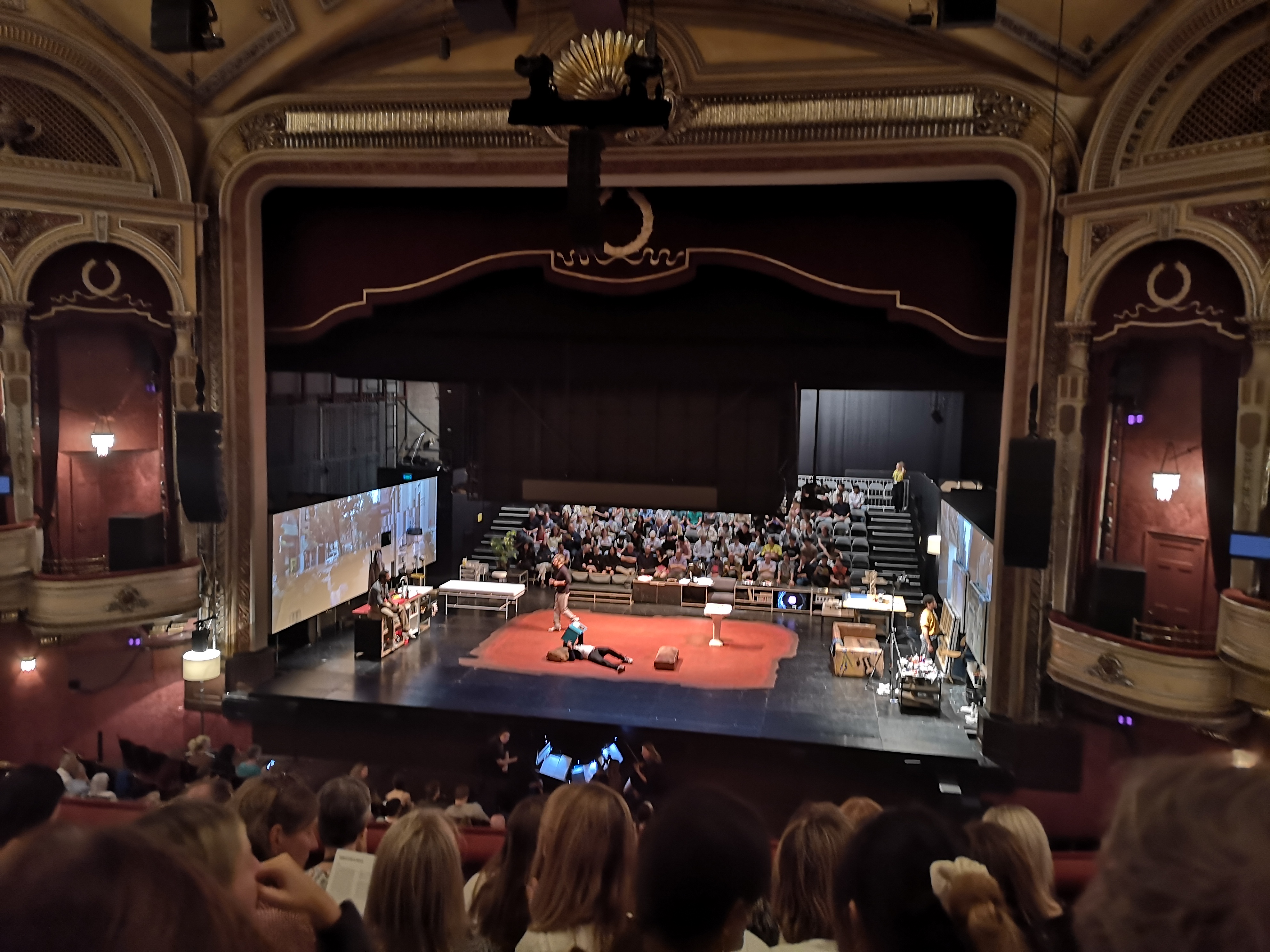 The stage of the Festival Theatre with the set of A Little Life - a red rectangle in the middle of the stage and two long screens on either side showing footage of New York city