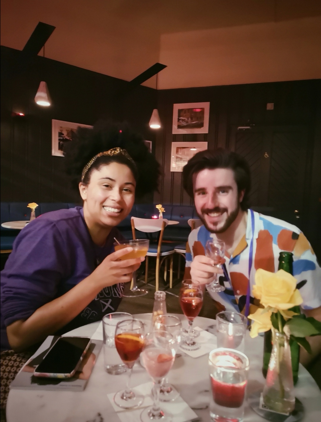 Two smiley faces look at me across a table of our drinks