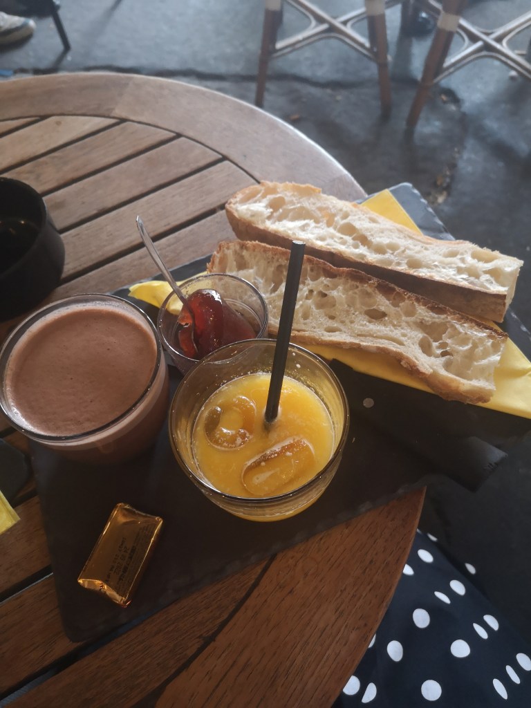 Breakfast of baguette with butter and jam, orange juice and hot chocolate