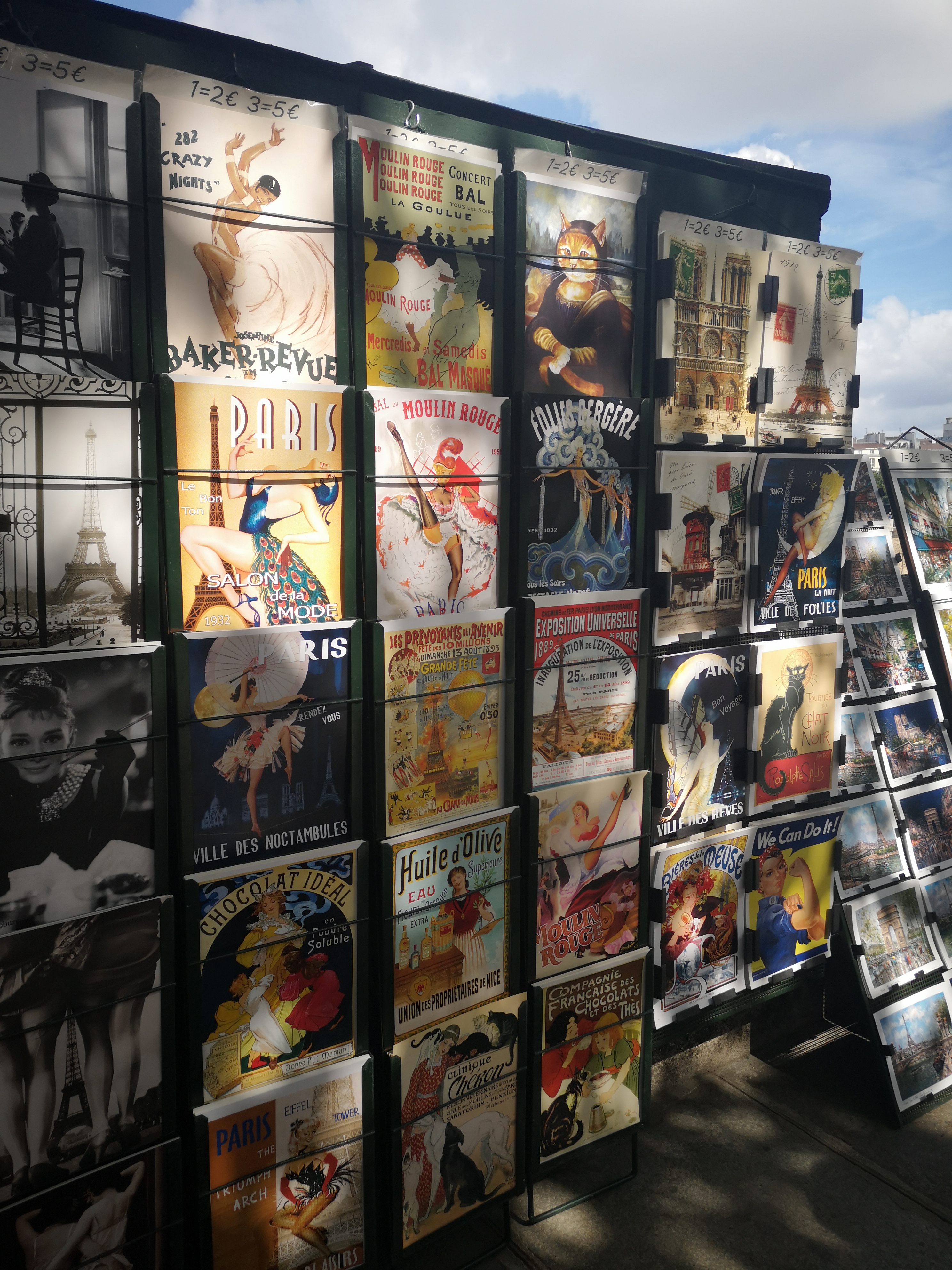 A stand filled with prints of old theatre posters, the sunlight through the trees shining on it