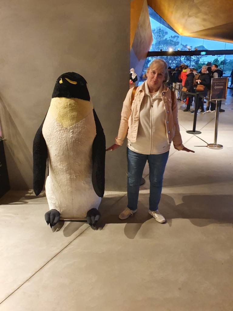 My cutie wee mam pretending to be a penguin beside a giant stuffed penguin toy