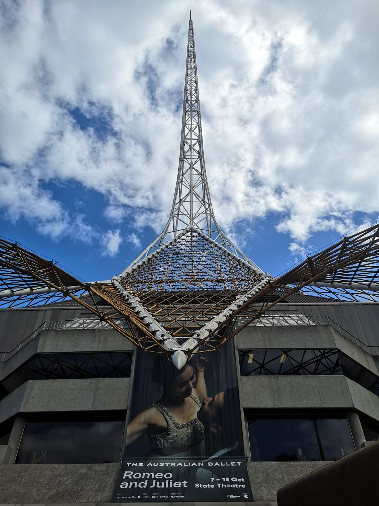 The big spire stretches up above the top of the Arts Centre against a blue sky