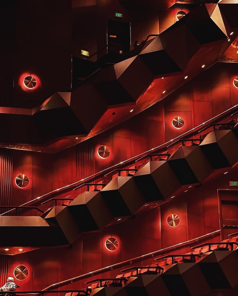 A close up of the balconies in a red, dimly lit theatre