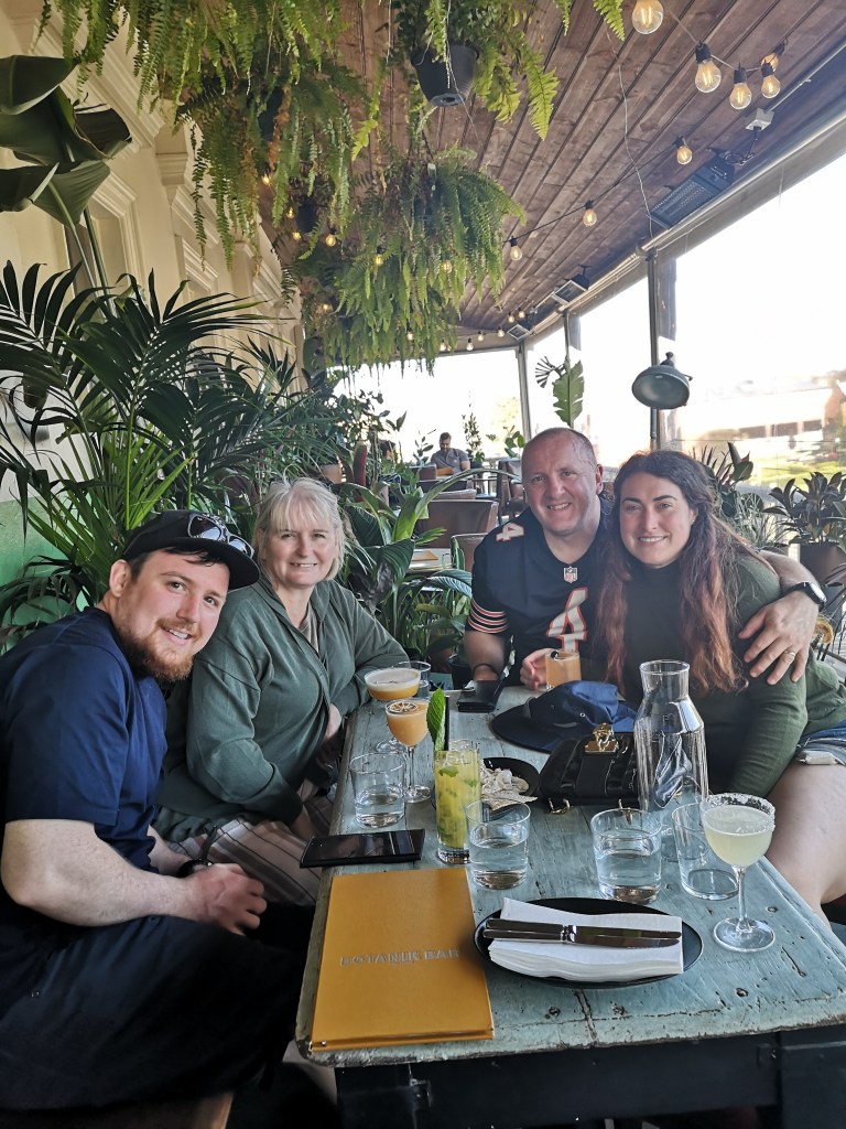 My parents and the newly married couple smile together in a cocktail bar