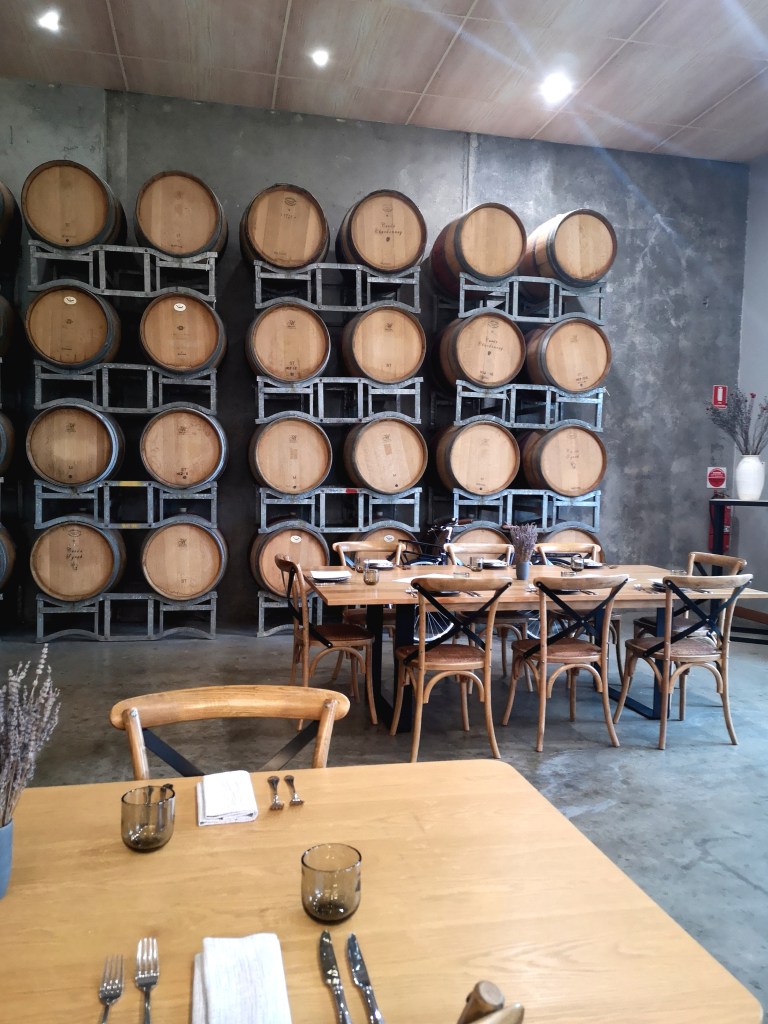 Stacks of barrels against a wall in front of dinner tables