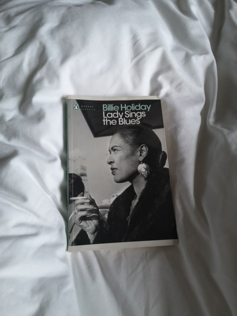 A copy og Lady Sings the Blues with Billie Holiday's face on it sits on a white duvet