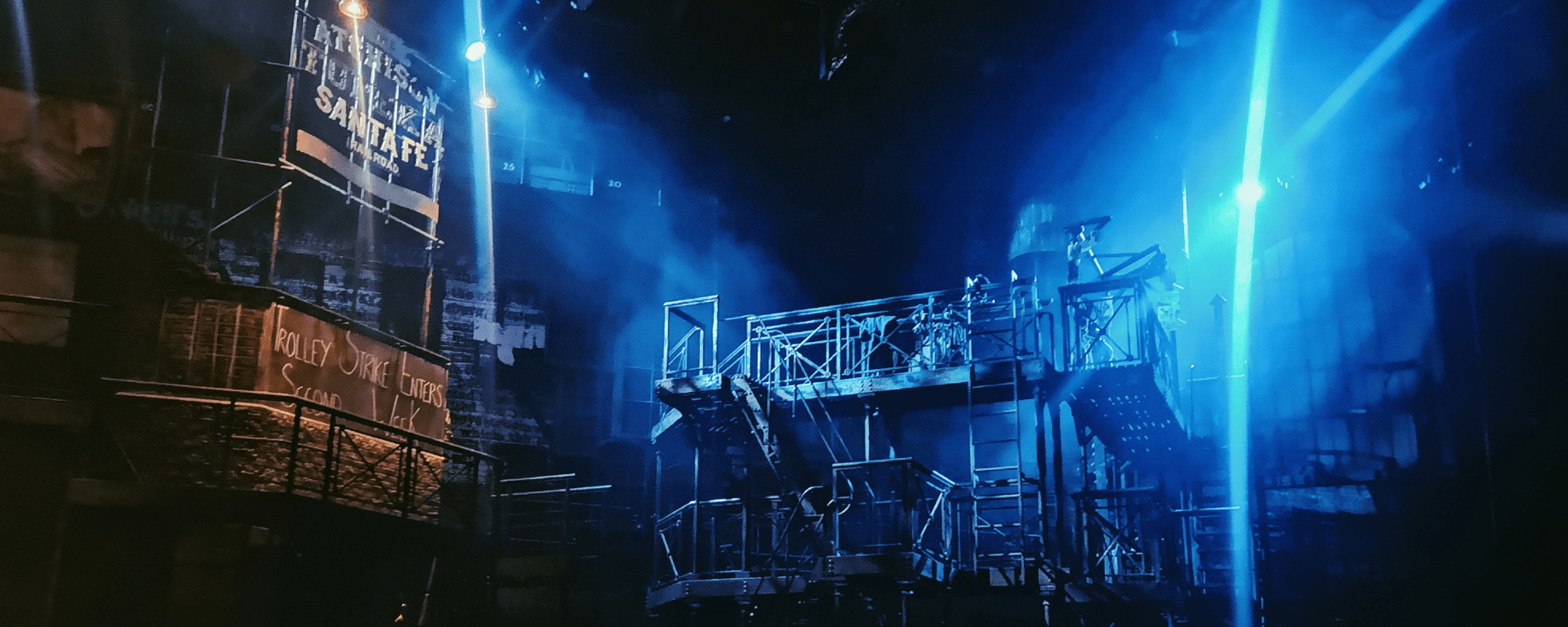Various platforms and ladders like an American fire escape shine under blue stage lights