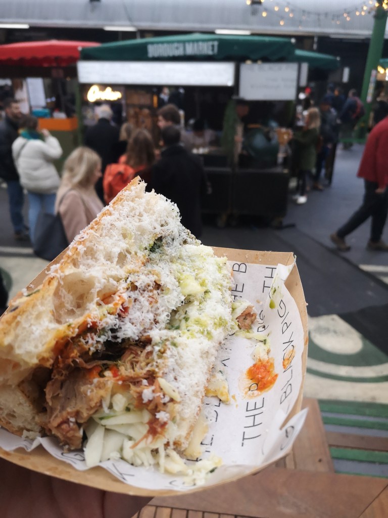 A pulled pork sandwich held up in front of a food truck