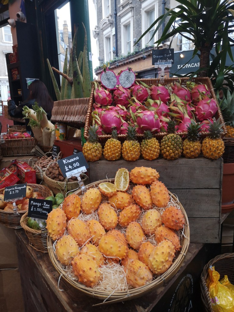 A market stall stacked with orange and pink tropical fruit