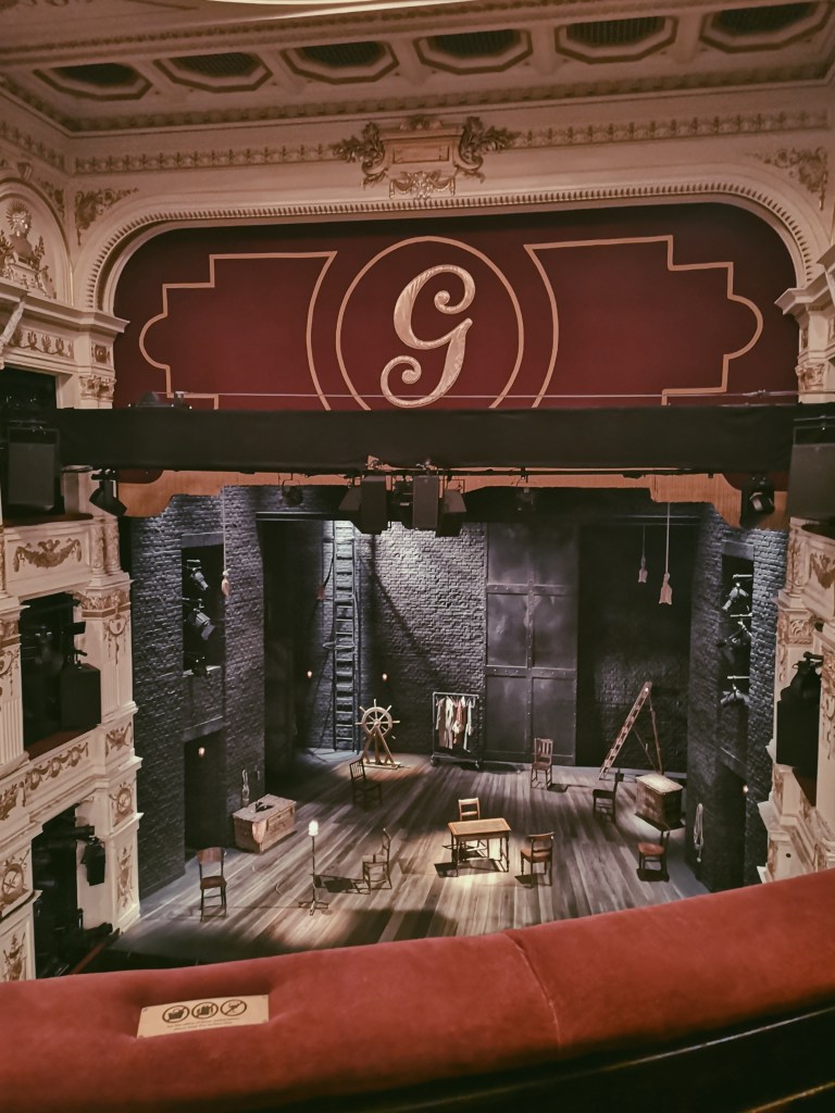 The inside of a theatre with various wooden items of furniture on stage