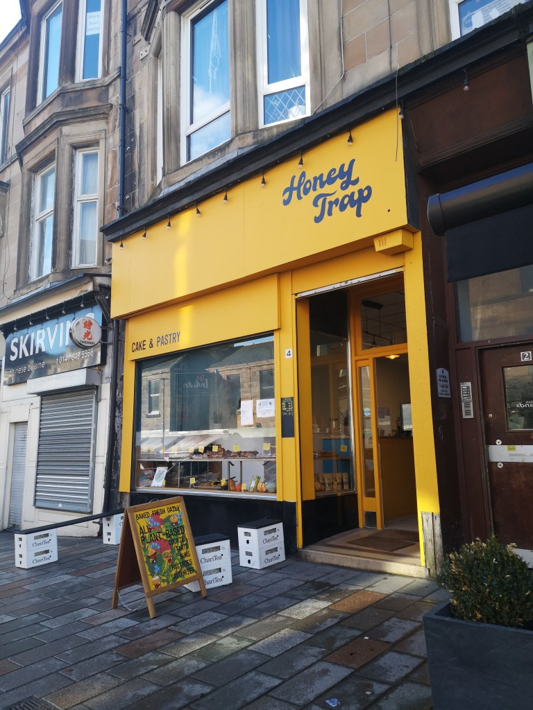 A yellow shop front that says Honey Trap bakery