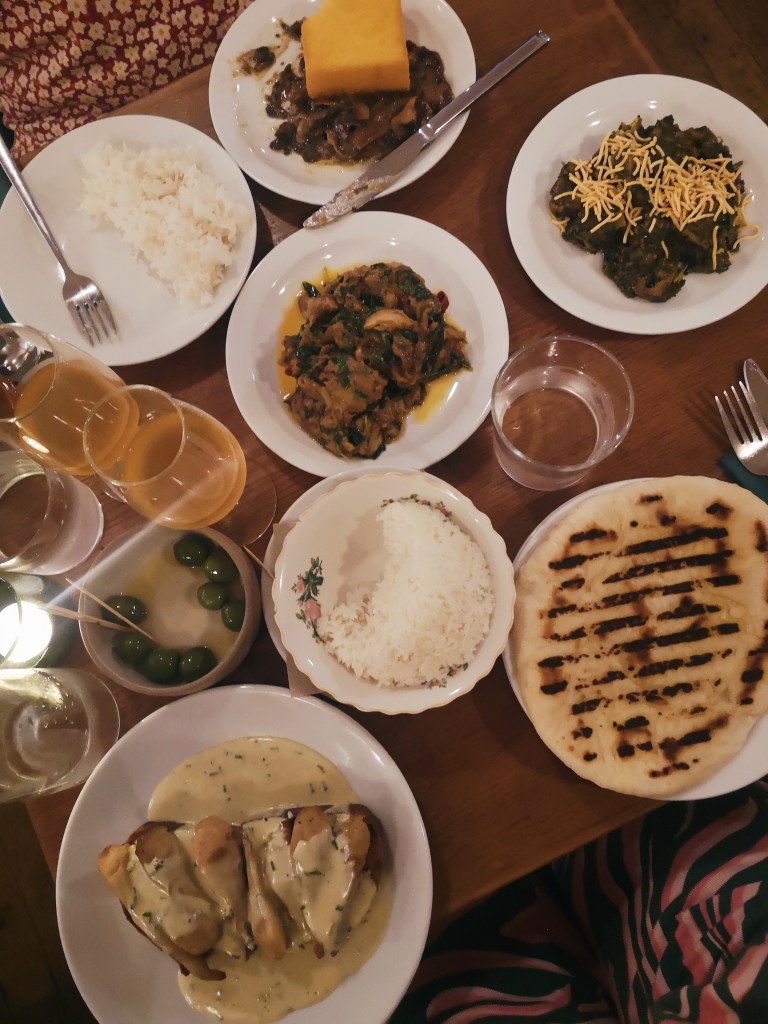 A dinner table loaded with vegetarian dishes and orange wine