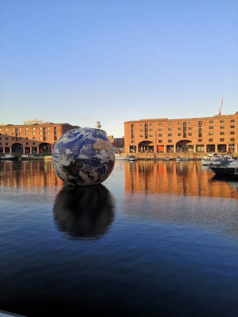 A large inflatable earth sits on the water surrounded by the docks