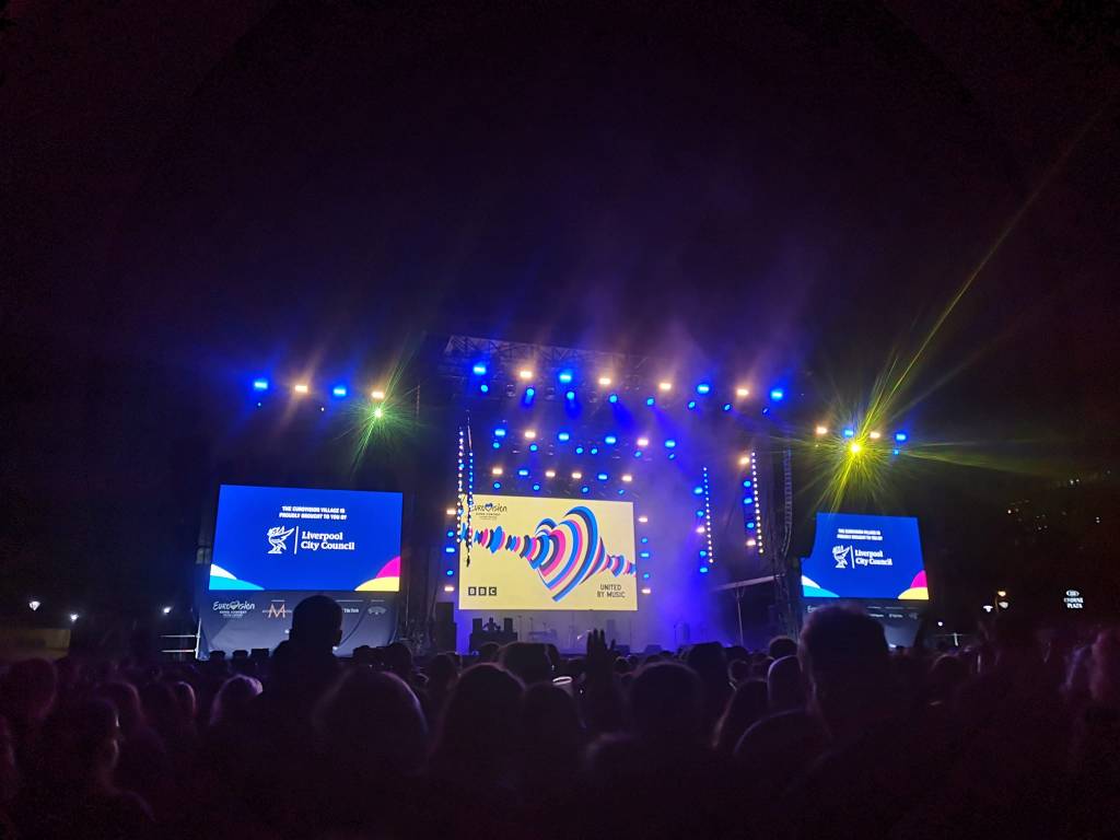 Blue and yellow stage lights shine on a crown with the Eurovision heart logo on the screen