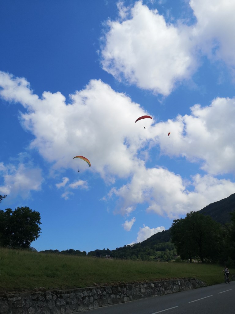 Paragliders hang in the sky in front of the clouds